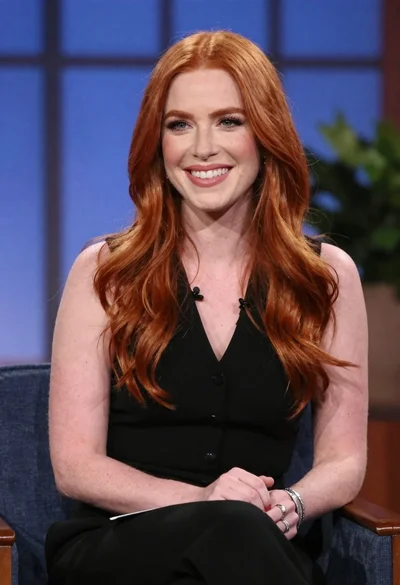 Smiling woman with red wavy hair in black top studio portrait