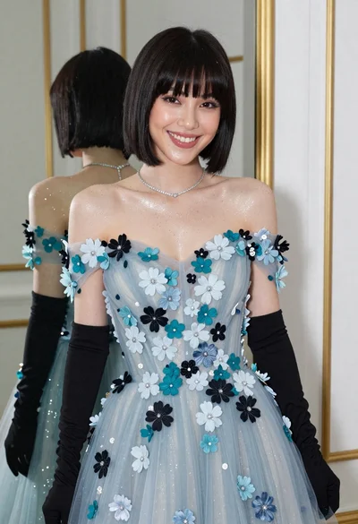 Smiling woman in blue floral dress posing before a mirror indoors