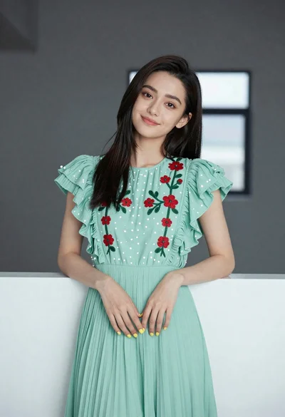 Young woman in light green embroidered dress leaning indoors
