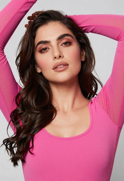 Close up portrait of woman with dark wavy hair in pink top