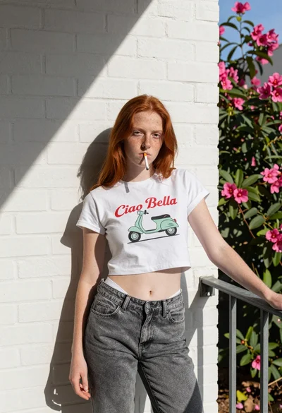 Young woman with red hair leaning against white brick wall in sunlight