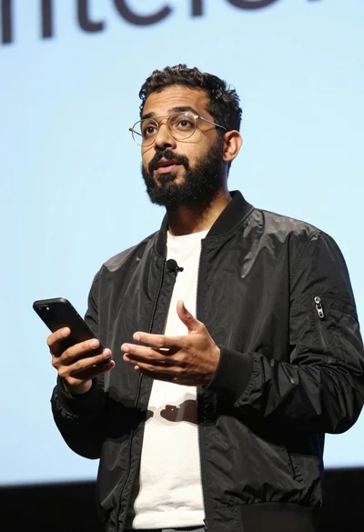 Man presenting on stage holding smartphone under strong dramatic lighting