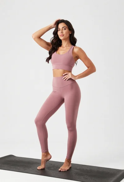 Fit woman in dusty pink sports bra standing on black yoga mat