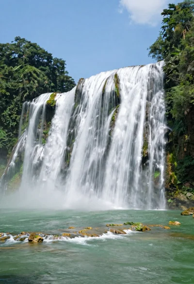 Majestic multitiered waterfall cascading into an emerald pool in tropical forest