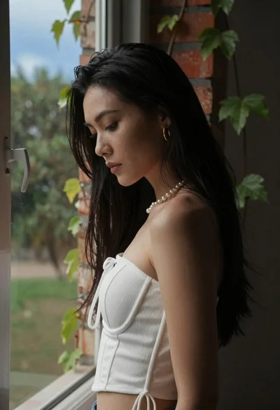 Woman in white top by window overlooking green ivy and trees