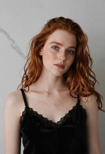 Soft focus portrait of young woman with red hair against grey marble