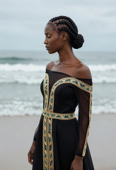 Profile portrait of woman in black gown against soft ocean backdrop