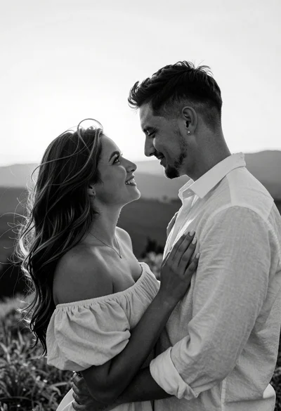Black and white portrait of embracing couple outdoors with soft backlighting