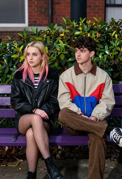 Two young adults sitting on a purple bench in an urban outdoor