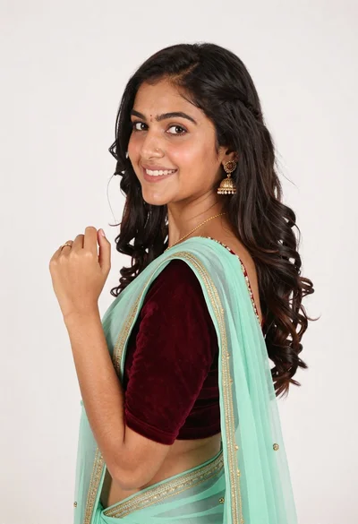 Smiling young woman in maroon velvet and mint saree studio portrait
