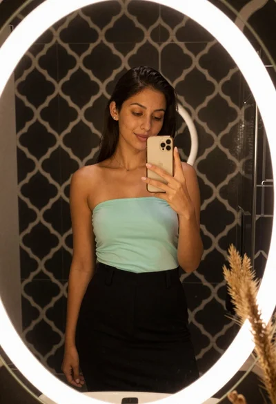 Young woman taking a mirror selfie in an oval tiled bathroom
