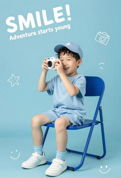 Happy young asian boy in blue outfit holding toy camera on solid
