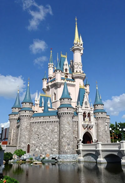 Majestic fairytale castle with blue roofs standing by a moat under bright