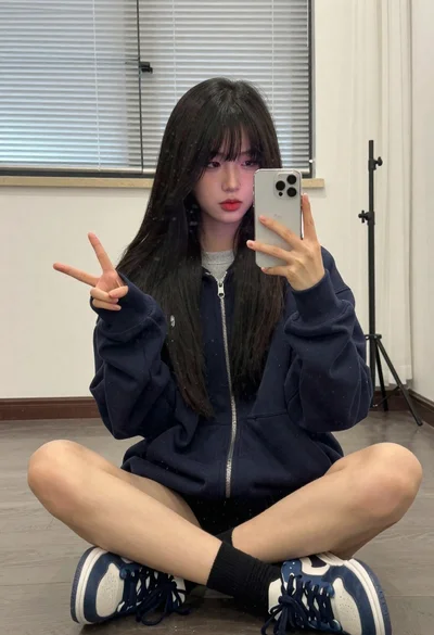 Young woman taking a mirror selfie in an indoor room setting
