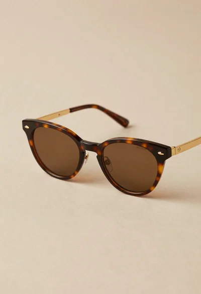 Stylish cateye sunglasses with tortoiseshell frame on beige surface