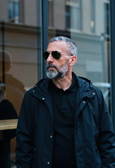 Portrait of man in black jacket by reflective glass window