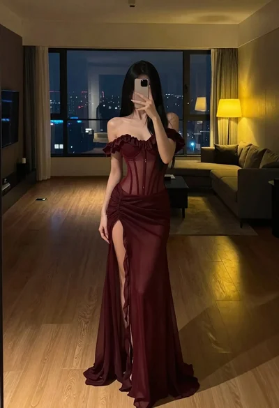 Woman in burgundy corset dress taking mirror selfie in modern room