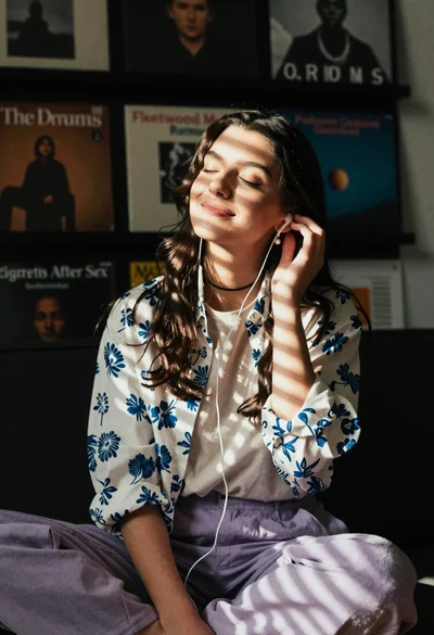 Young woman in floral shirt listening to music with closed eyes in