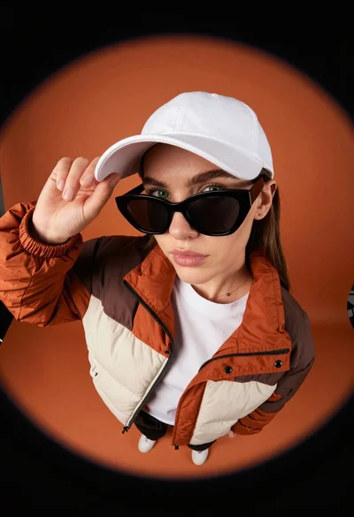 Young woman in puffer jacket and white cap looking up at camera