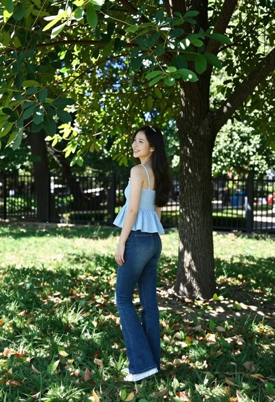 Young woman in blue stripes on grassy lawn under large shady tree