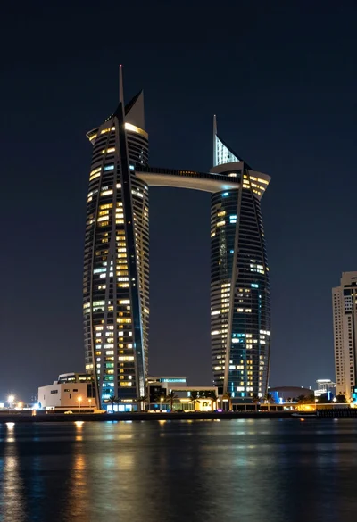 Wide angle view of towering sail skyscrapers reflecting in dark waterfront at