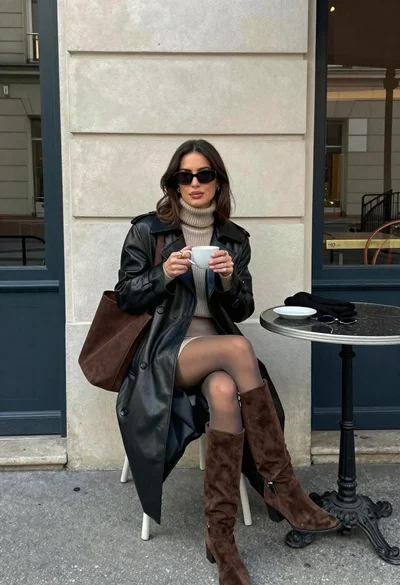 Stylish woman in leather coat sitting at an outdoor cafe table