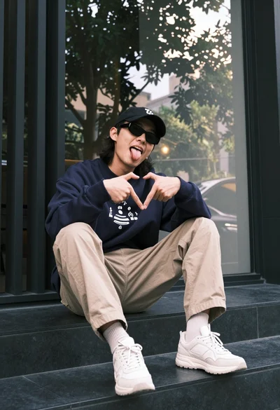 Man sitting casually outdoors in streetwear near glass window facade