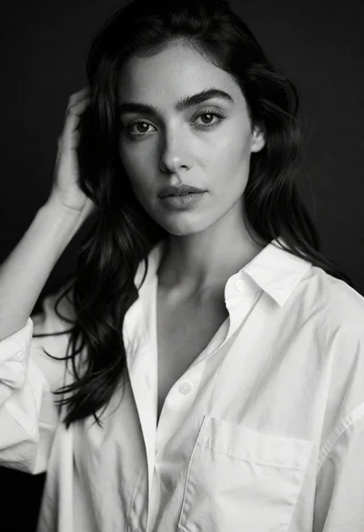 Black and white portrait of woman touching dark hair in studio setting