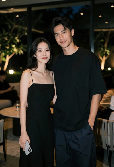 Couple standing indoors at night near glass windows with garden view