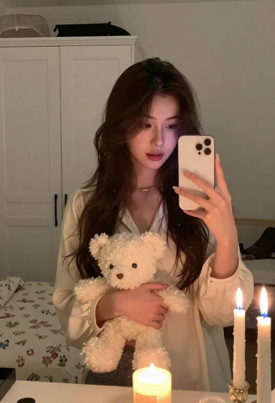 Young woman in cream blouse holding white teddy bear for mirror selfie