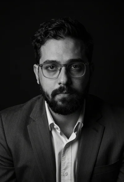 Black and white studio portrait of man with beard wearing dark suit