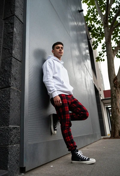 Young man leaning against textured metal wall in urban alleyway setting