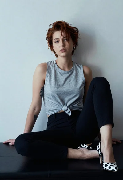 Young woman with reddish brown hair seated on dark leather surface