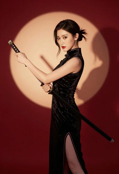 Woman in black velvet cheongsam holding katana against red background