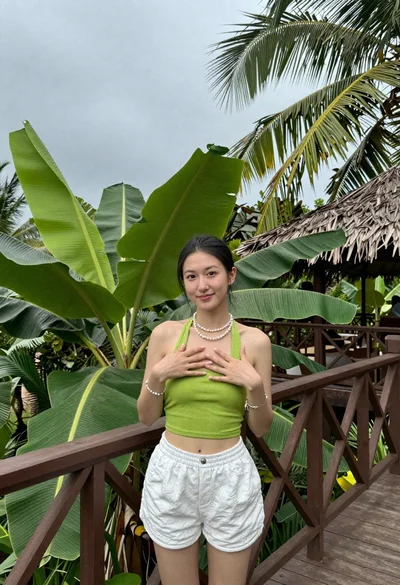 Young woman on wooden deck surrounded by tropical foliage under overcast sky