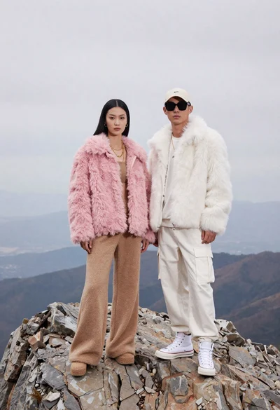 Two models on a rocky mountain peak under overcast sky