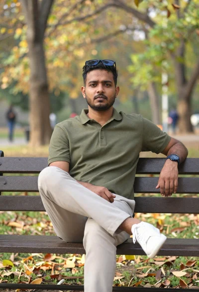 South asian man on park bench with autumn background