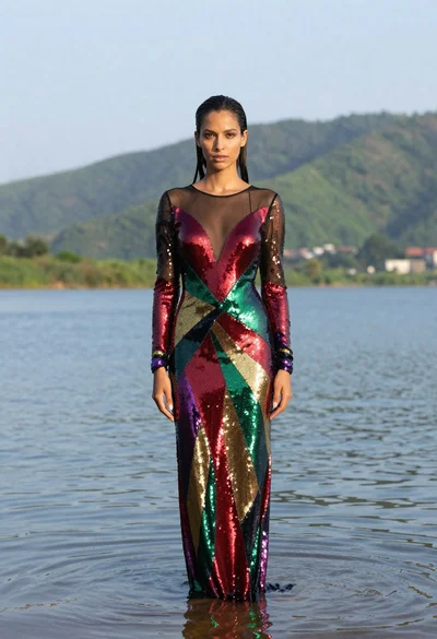Woman in sequined gown standing waist deep in calm water outdoors