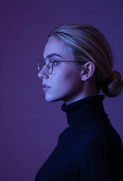 Young woman with blonde hair in low bun wearing glasses and dark