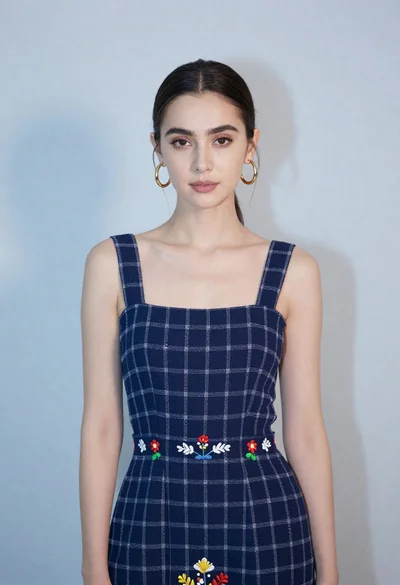 Poised young woman in dark blue embroidered dress studio portrait