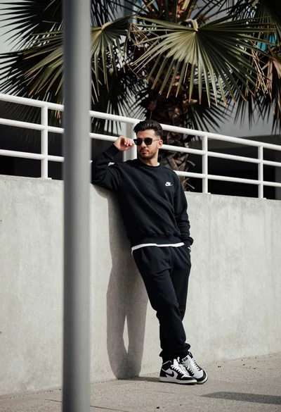 Stylish man leaning against concrete wall in an urban outdoor setting