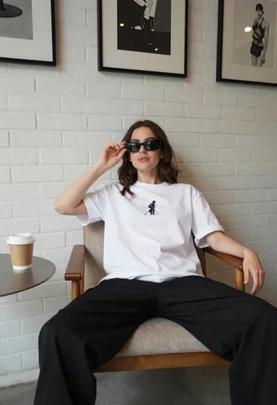 Young woman in white tshirt seated indoors near brick wall art