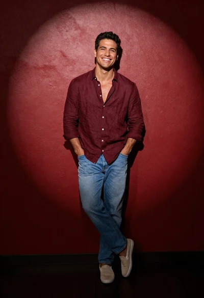 Full body studio portrait of smiling man in maroon shirt against red