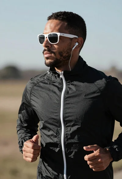Close up profile of determined man jogging outdoors with athletic jacket