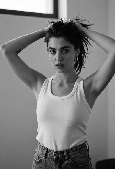 Monochrome portrait of woman adjusting dark hair indoors with natural light