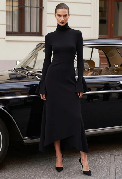 Woman in black dress standing by vintage car