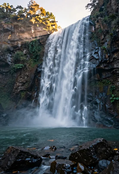 Majestic waterfall cascading over rugged cliff face into serene pool