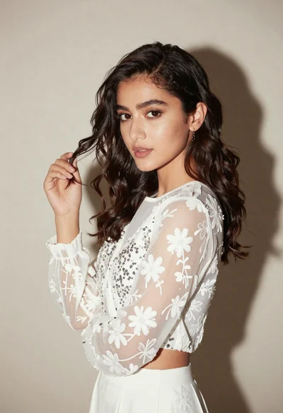 Young woman in white embroidered blouse posing against a plain studio background