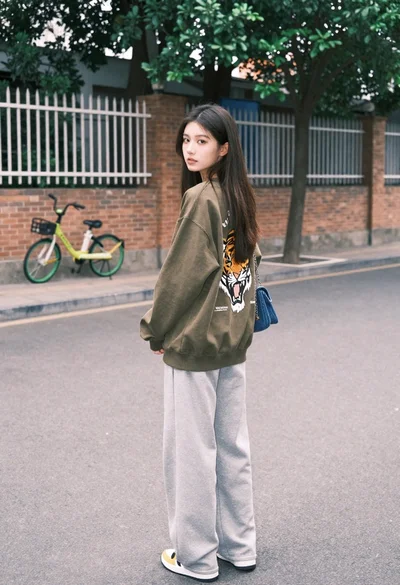 Young woman looking back over shoulder on paved street with bicycle