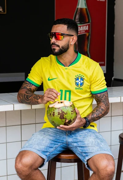 Muscular man in brazil jersey holding coconut at tiled bar counter
